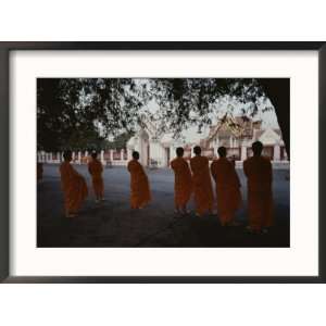  Buddhist monks in orange robes stand outside an ornate 
