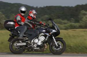 Two people riding a motorcycle and wearing protective motorcycle gear